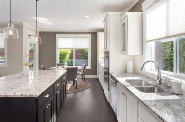 beautiful kitchen in new luxury home with island, pendant lights, oven, range, and hardwood floors.